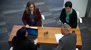 overhead view of three women and a man discussing at a table