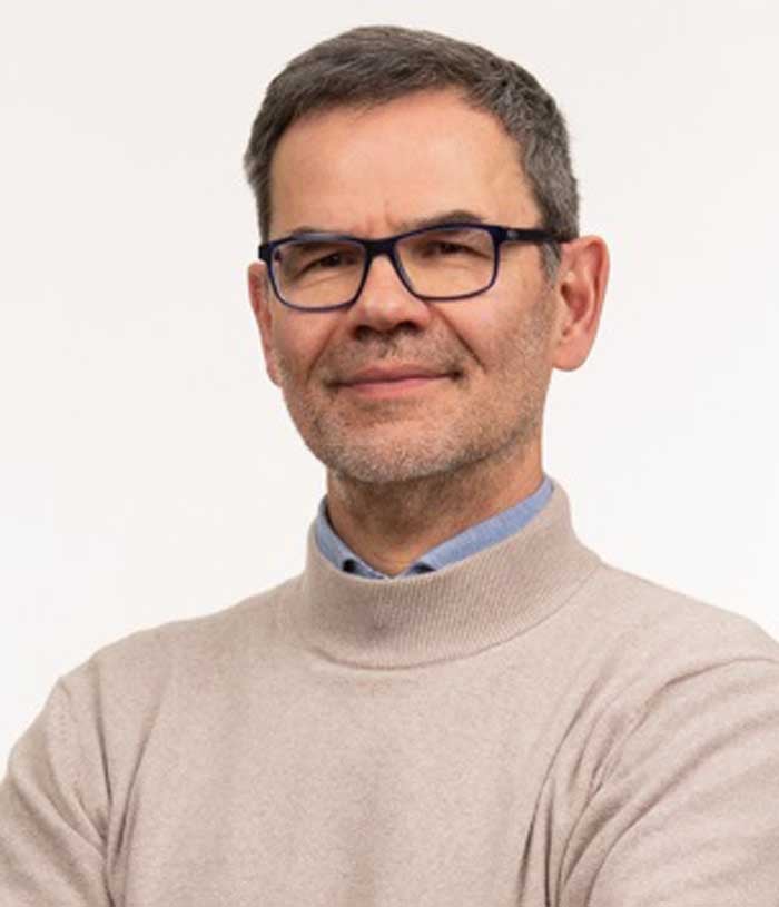 Baziel van Engelen, a man with dark hair and rectangular glasses, wears a tan turtleneck sweater over a blue button-down shirt.