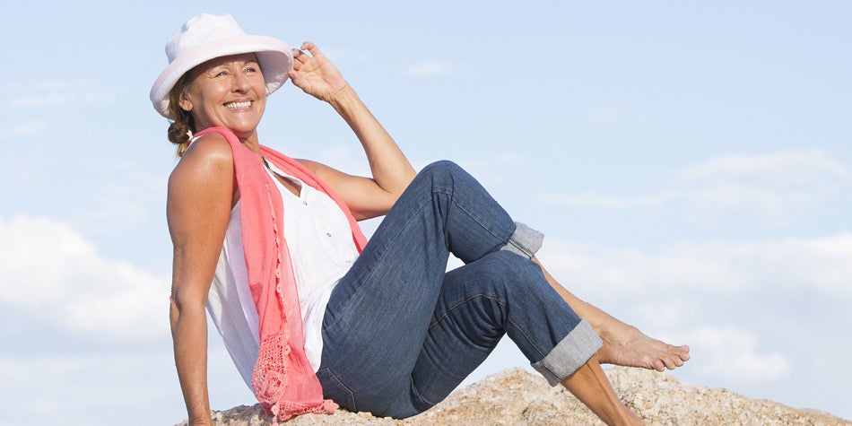 Women on beach with sitting on sand smiling.