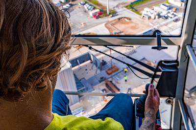 Crane operator looks down below on construction site