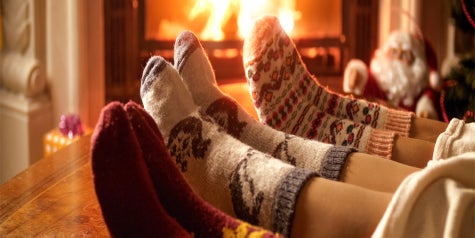 Three sets of feet wearing socks by the fireplace