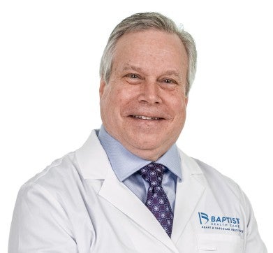 Dr. James Taylor is pictured wearing his doctors' jacket for Baptist Medical Group. He is wearing a light blue shirt and dark blue tie and is smiling at the camera.