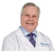 Dr. James Taylor is pictured wearing his doctors' jacket for Baptist Medical Group. He is wearing a light blue shirt and dark blue tie and is smiling at the camera.