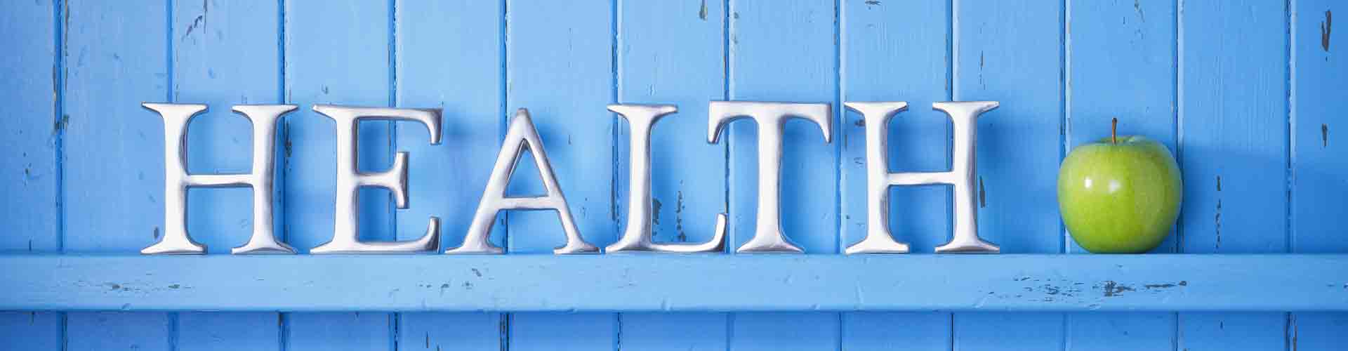 Wooden letters on shelf spelling out Health and a green apple next to it