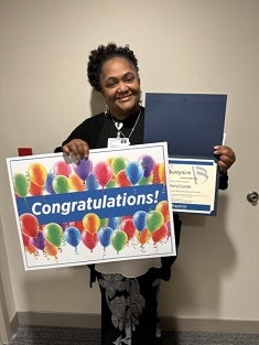 Cheryl Locke, a Black female smiles proudly with her Champion award recognition