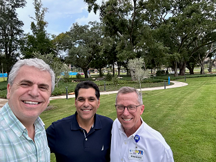 Doctors Thabet Alsheikh and Razek and John Porter smile and pose in front of the three planted olive trees.