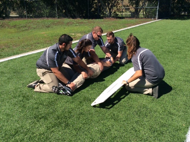 Instructor teaching student CPR on CPR mannequin.