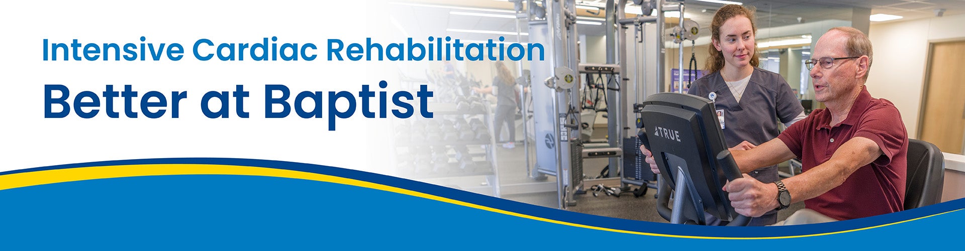 Heart team member standing next to rehab patient on exercise bike.