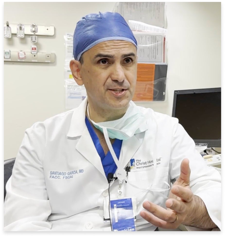 Dr. Santiago A. Garcia in a white coat and surgical cap, speaking in a hospital office