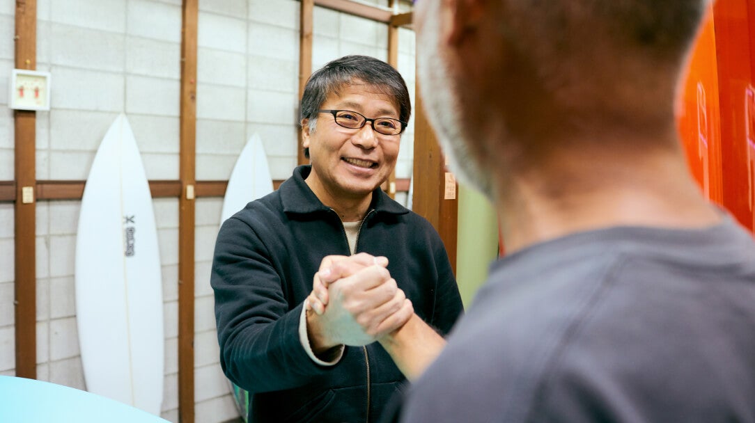 Men shaking hand at surfboard shop