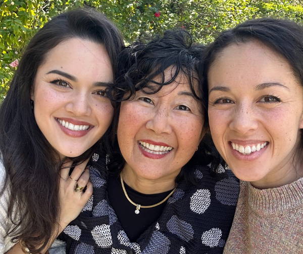 Emi Grannis on the left, hugging her mom. Trish (Mama G) Grannis is in the middle with her daughter, Kina Grannis standing up against her on the right.  