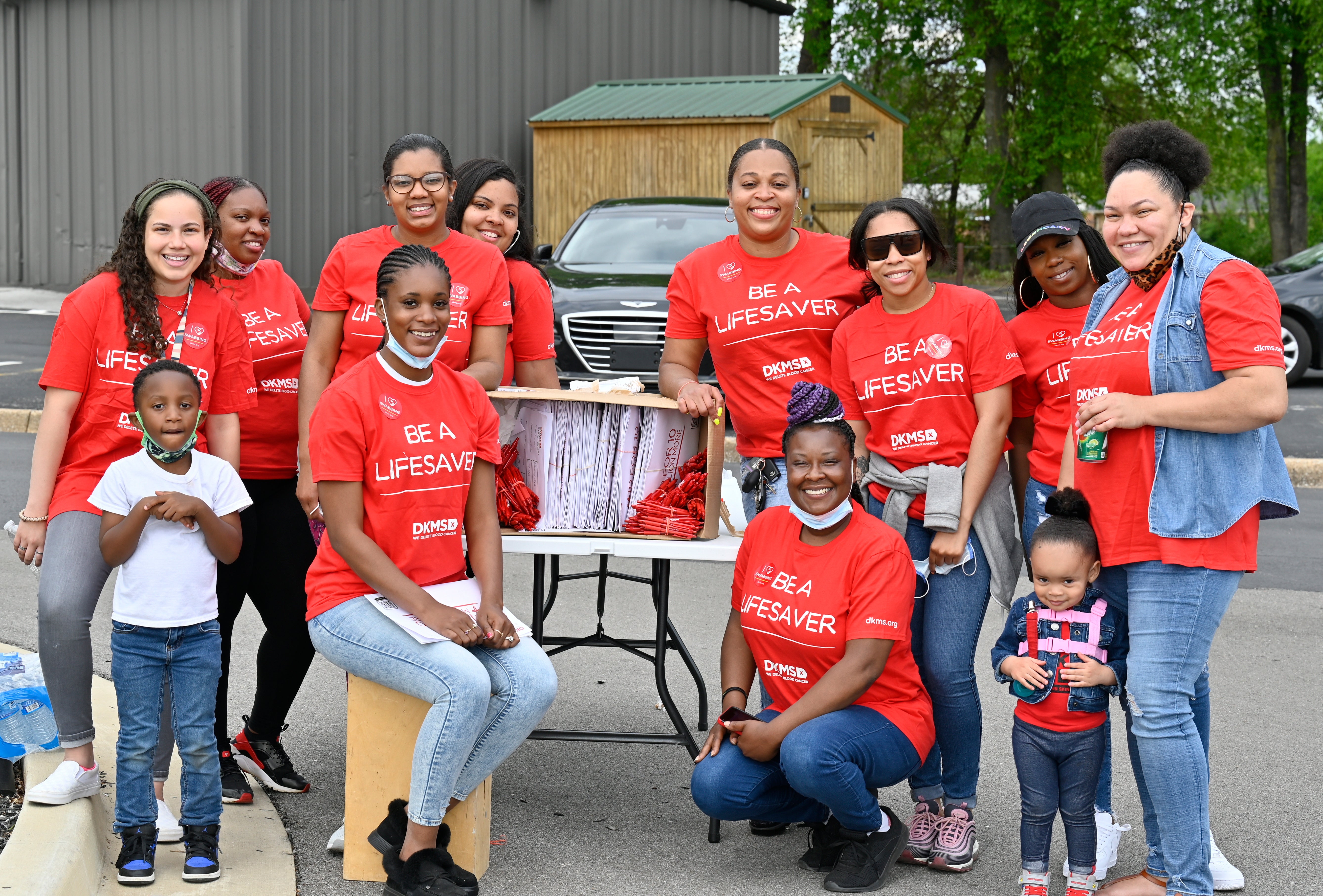 DKMS bone marrow donor registration drive volunteers pose for a photo with their completed registration kits. 