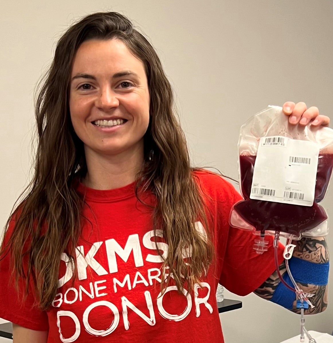 DKMS donor, Aimee, holding her stem cells in her DKMS donor shirt