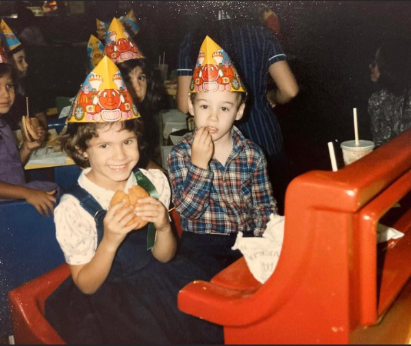 Alyson and Michael as young kids wearing party hats and eating burgers