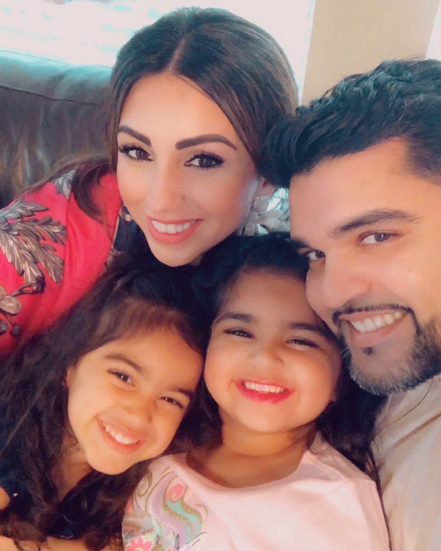 Dr. Omar Durani and his family - wife and two daughters - cuddle together and smile. 