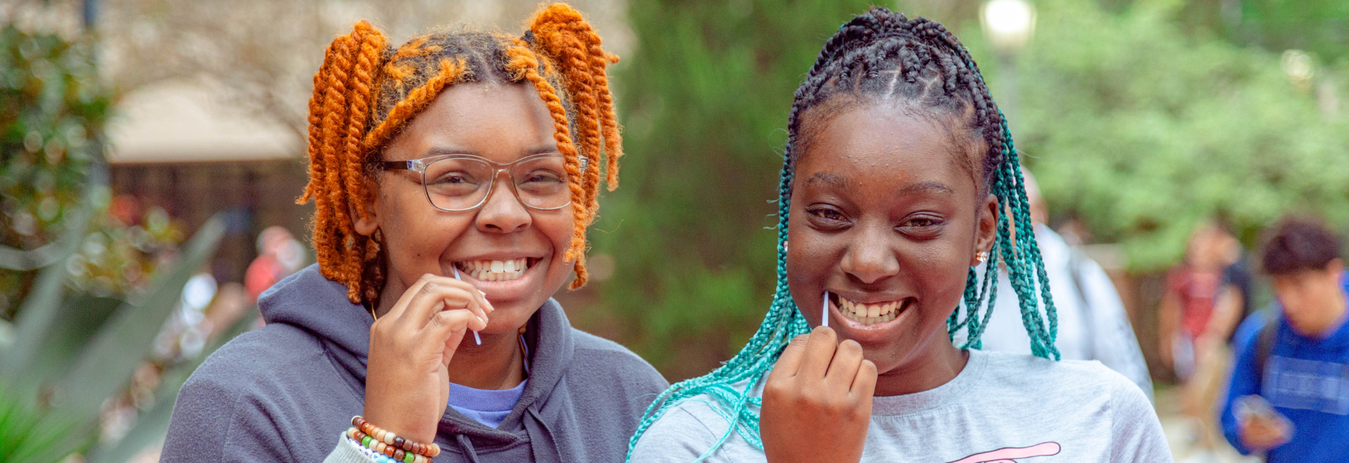 Two girls swabbing to become a blood stem donor with DKMS
