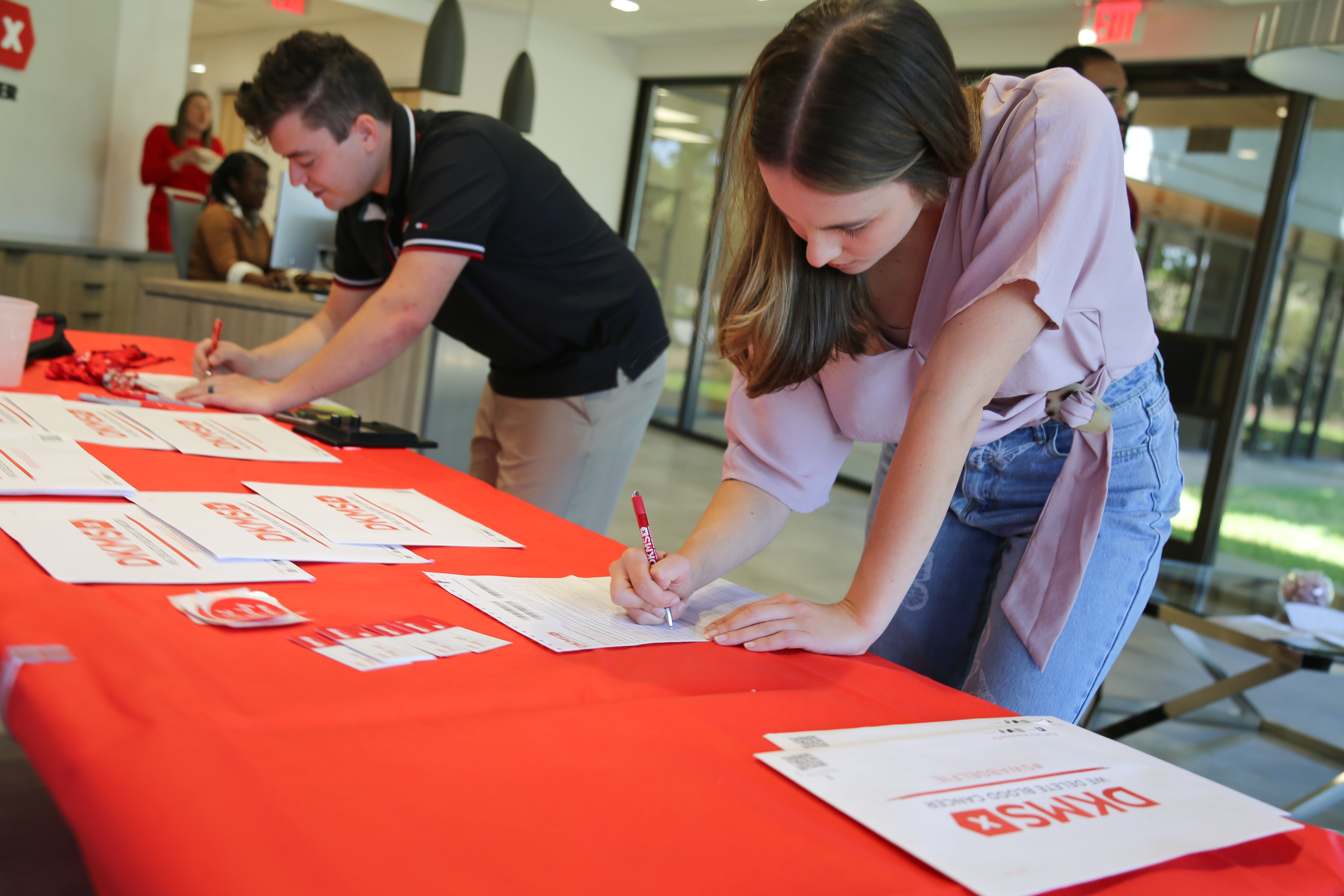 Two attendees at the Charlotte Media event start the registration process by filling out their registration forms. 