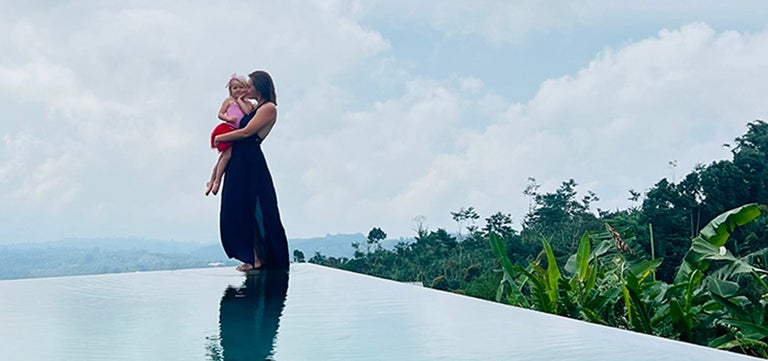 A woman holding a baby on a pool edge
