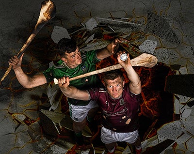 2 men holding hurls and sliotar