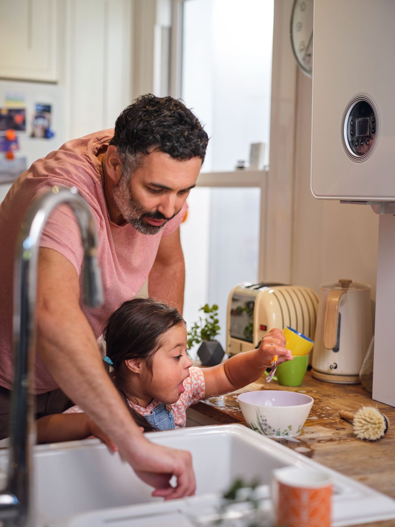 Father washing dishes with child