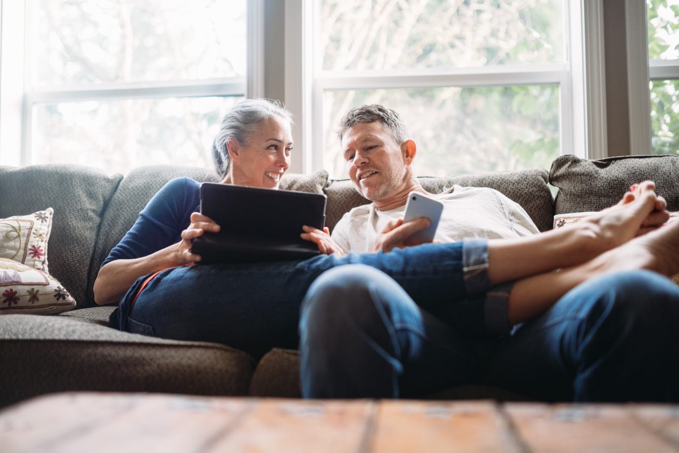 Couple sitting on sofa with ipad and phone in hand