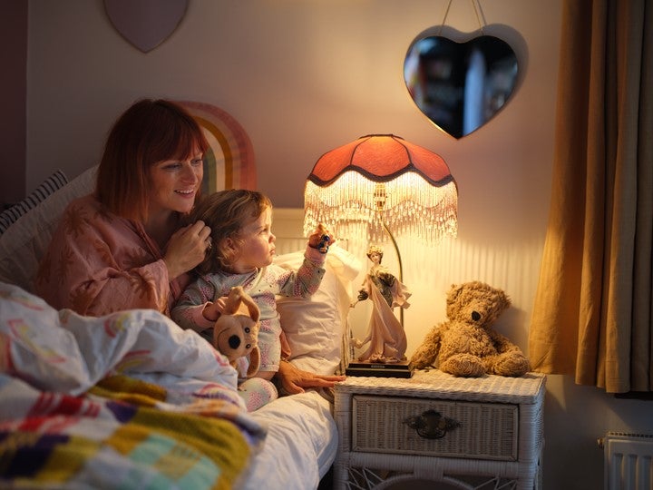 woman with infant child in bed switching off light