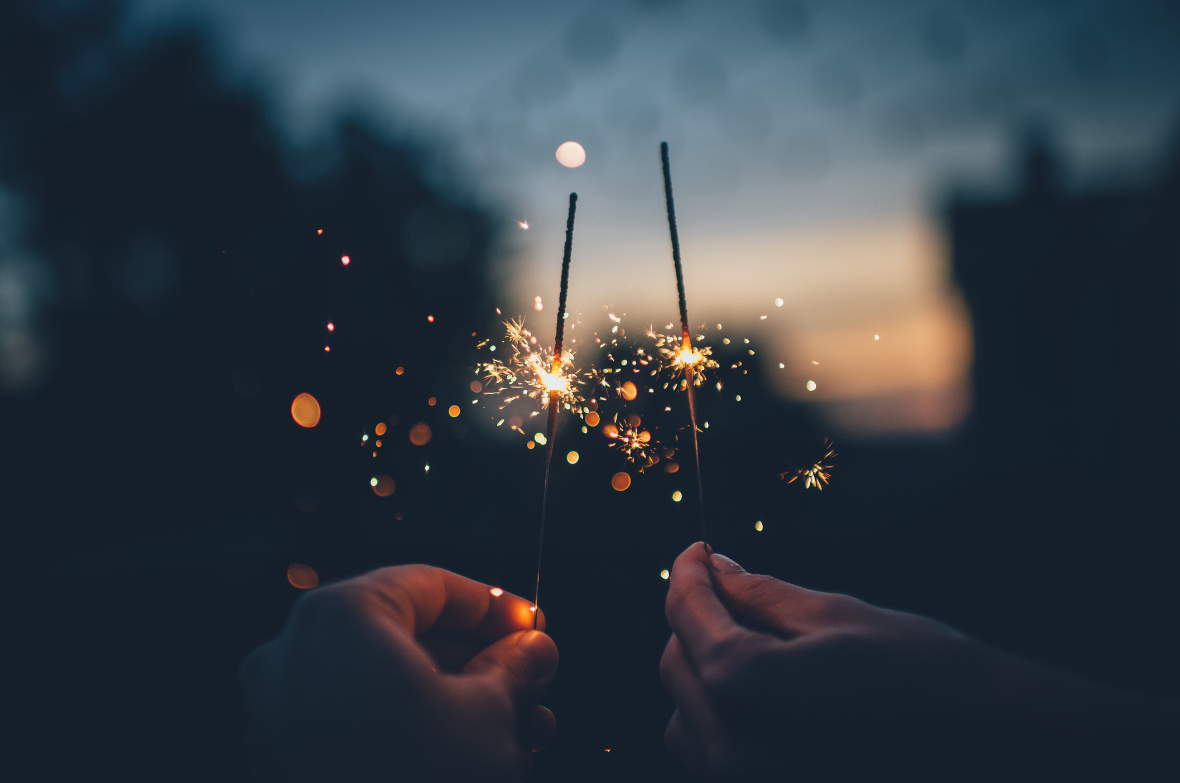 Two sparklers lit in an evening sky
