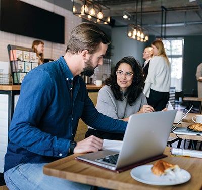 Man and woman working on laptops at a coffee shop