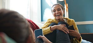 Person lounging indoors on a sofa, wearing a yellow knitted cardigan and holding a smartphone