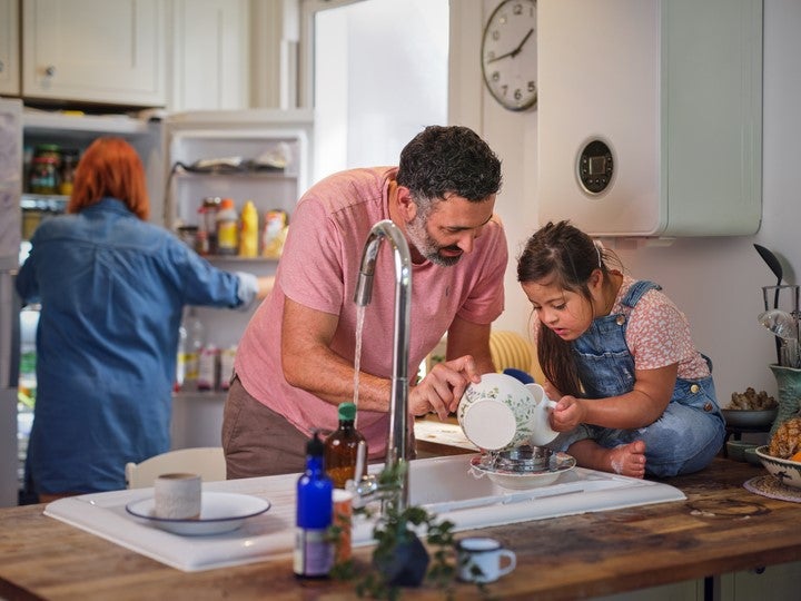 Father and daughter in kitchen washing dishes