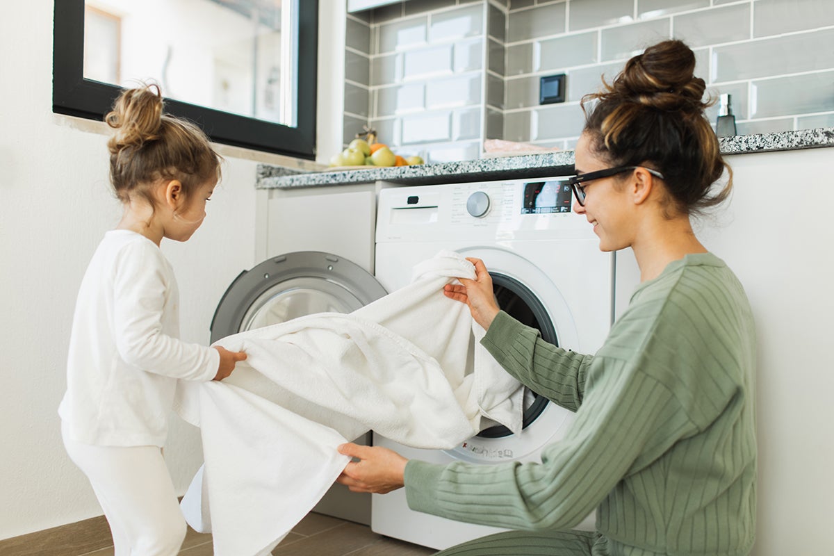 mother and daughter taking clothes out of washing machine