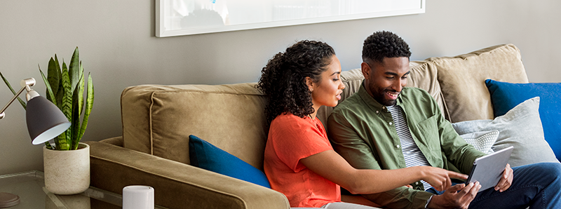 Couple sitting on a couch looking at a laptop