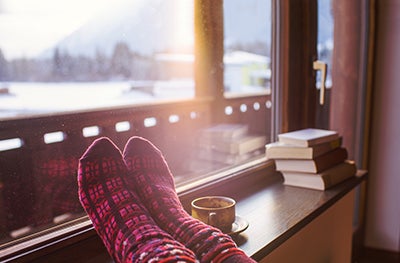 Cosy socks on feet on a window ledge with snowy landscape