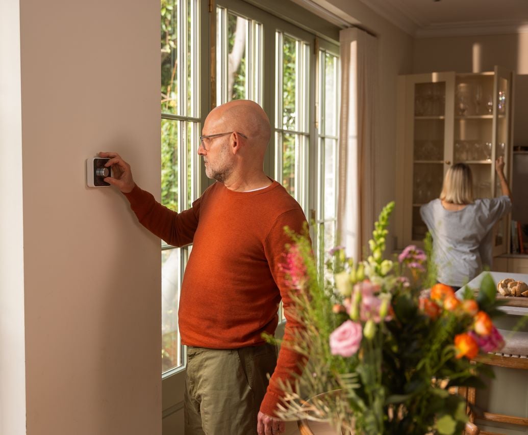 Man in kitchen using smart thermostat