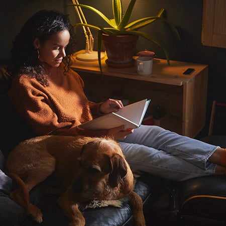 Woman reading book next to dog