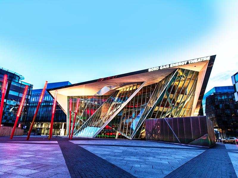 Exterior of Bord Gáis Energy Theatre in Dublin Docklands, modern glass-fronted venue illuminated at dusk