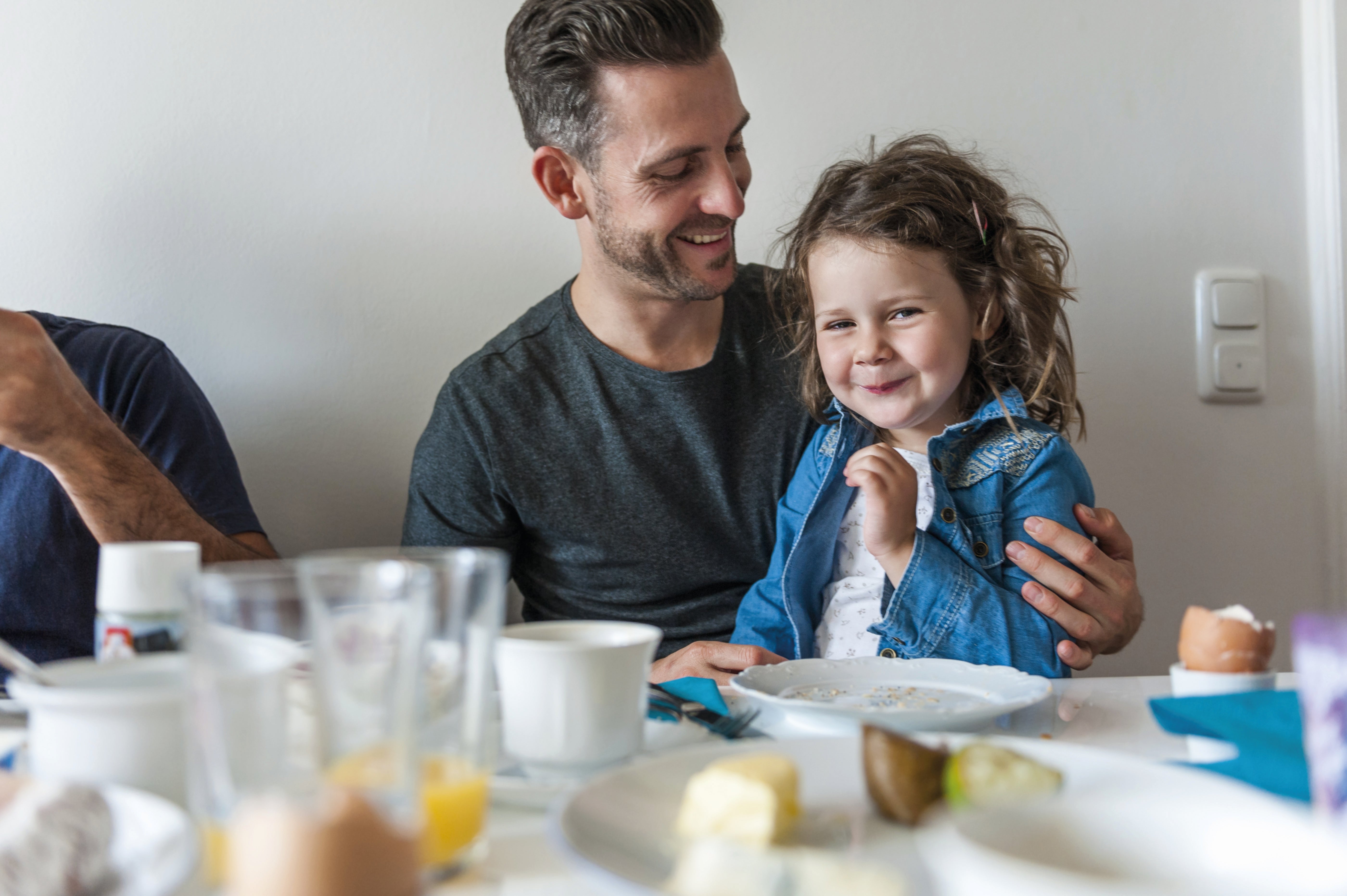 Man at breakfast table, looking at smiling little girl