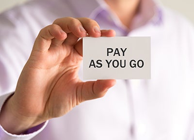 Man holding sign reading "pay as you go"