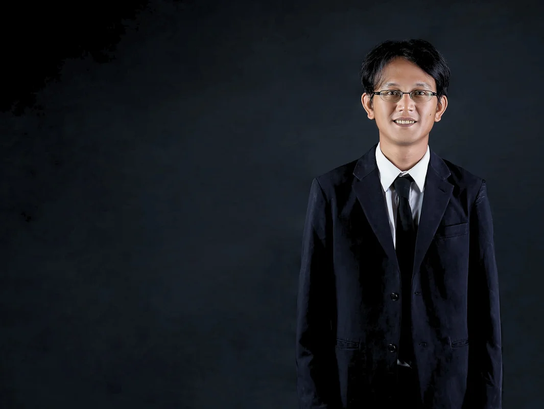 Indonesian man smiling in a suit on black background