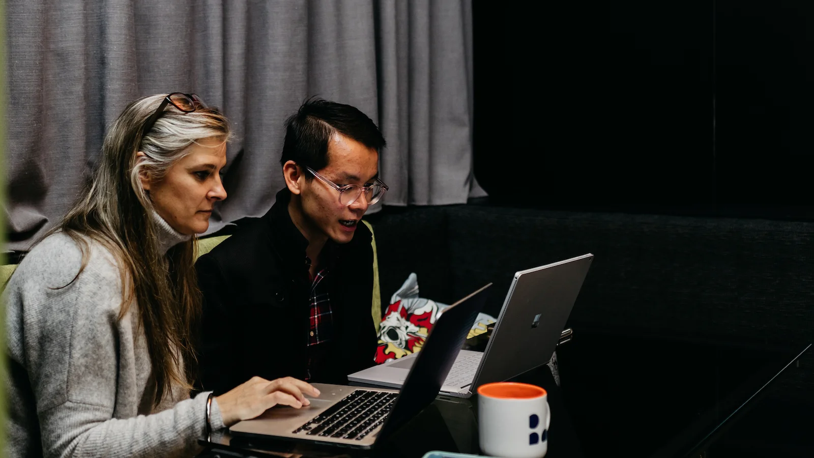 Man and woman having conversation over laptops
