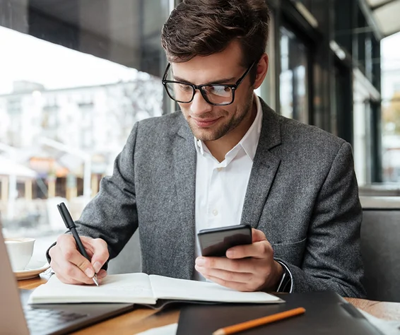man in a suit writing on a notebook