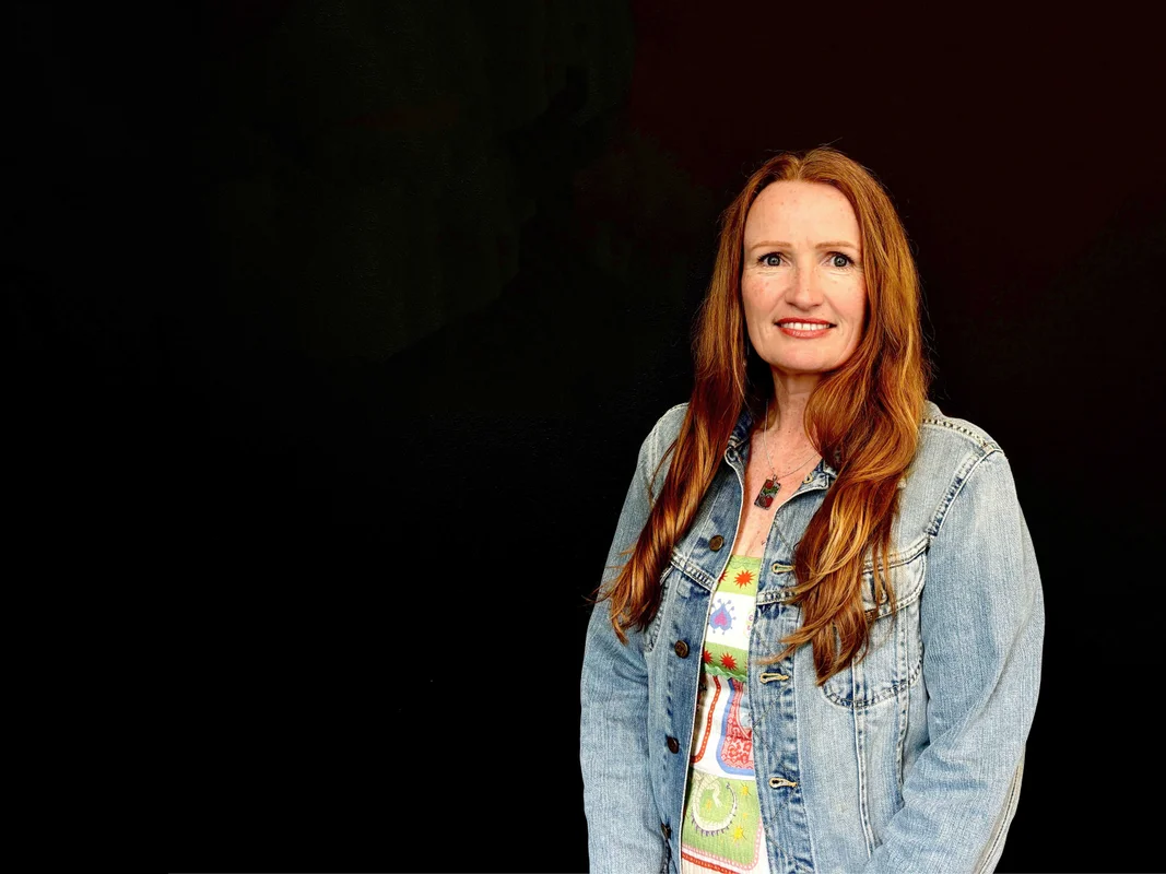 Red haired lady, smiling on a black background 