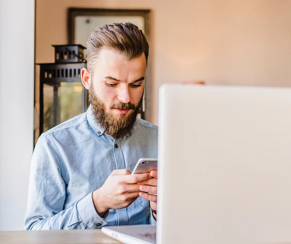 man holding a phone in front of a laptop