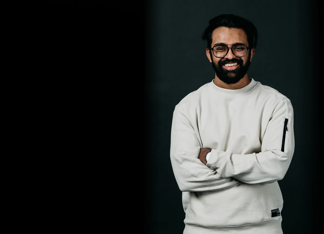 Picture of Luminary employee, Adi smiling at the camera with a black background.