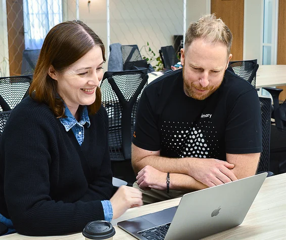 man and woman staring at a laptop a screen