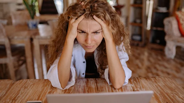 A woman looking frustrated sitting at a laptop