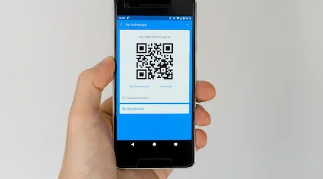 A person holding a phone displaying a QR code