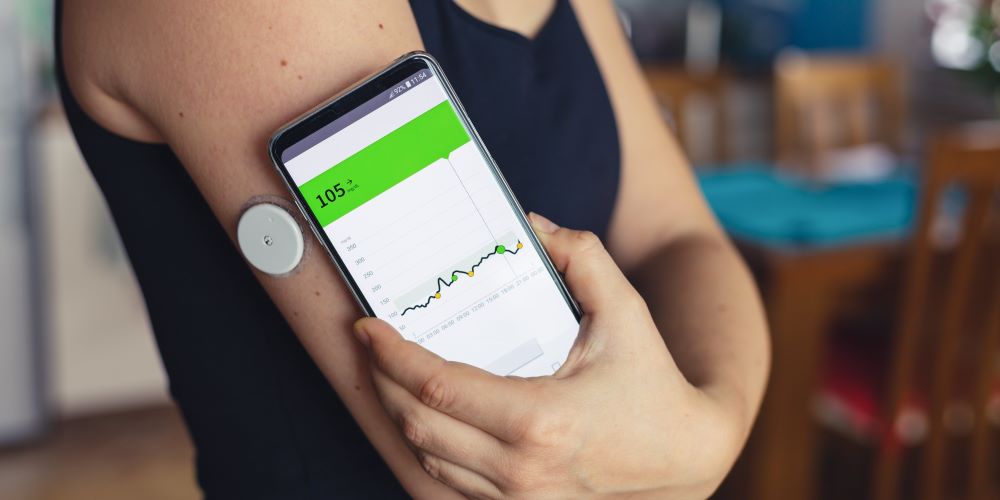 A person with glucose monitoring sensor checking the glucose value with smartphone