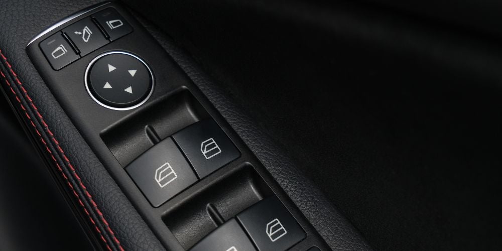 Automotive door control panel with power window switches and side‑view mirror adjustment controls, representative of body electronics systems driven by specialized motor driver ICs.