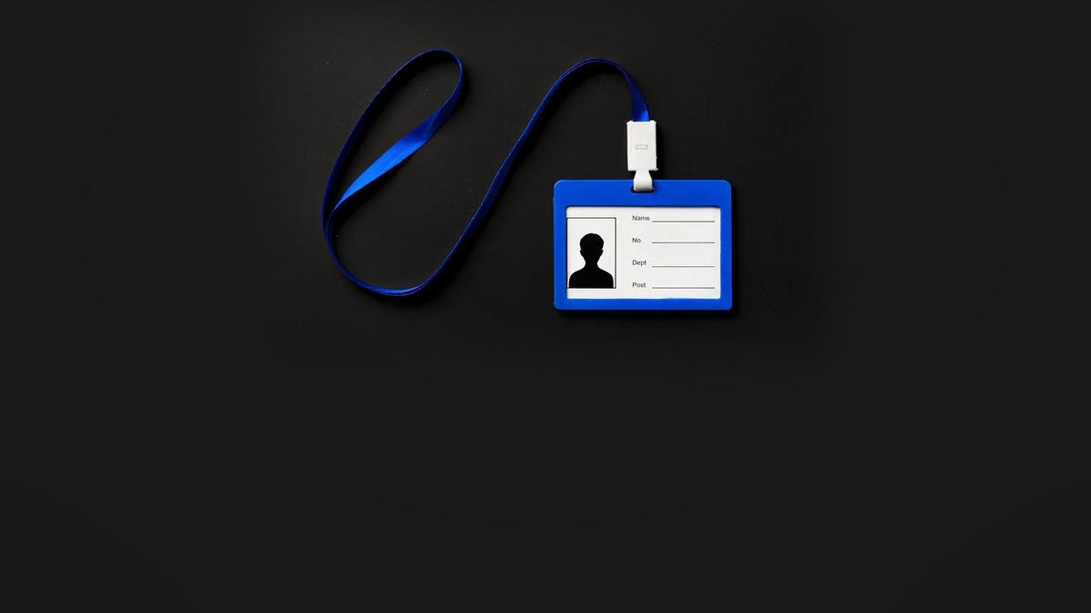 Blank blue lanyard ID badge lying on a black surface, with empty Name, Number, Department and Post fields and a placeholder silhouette